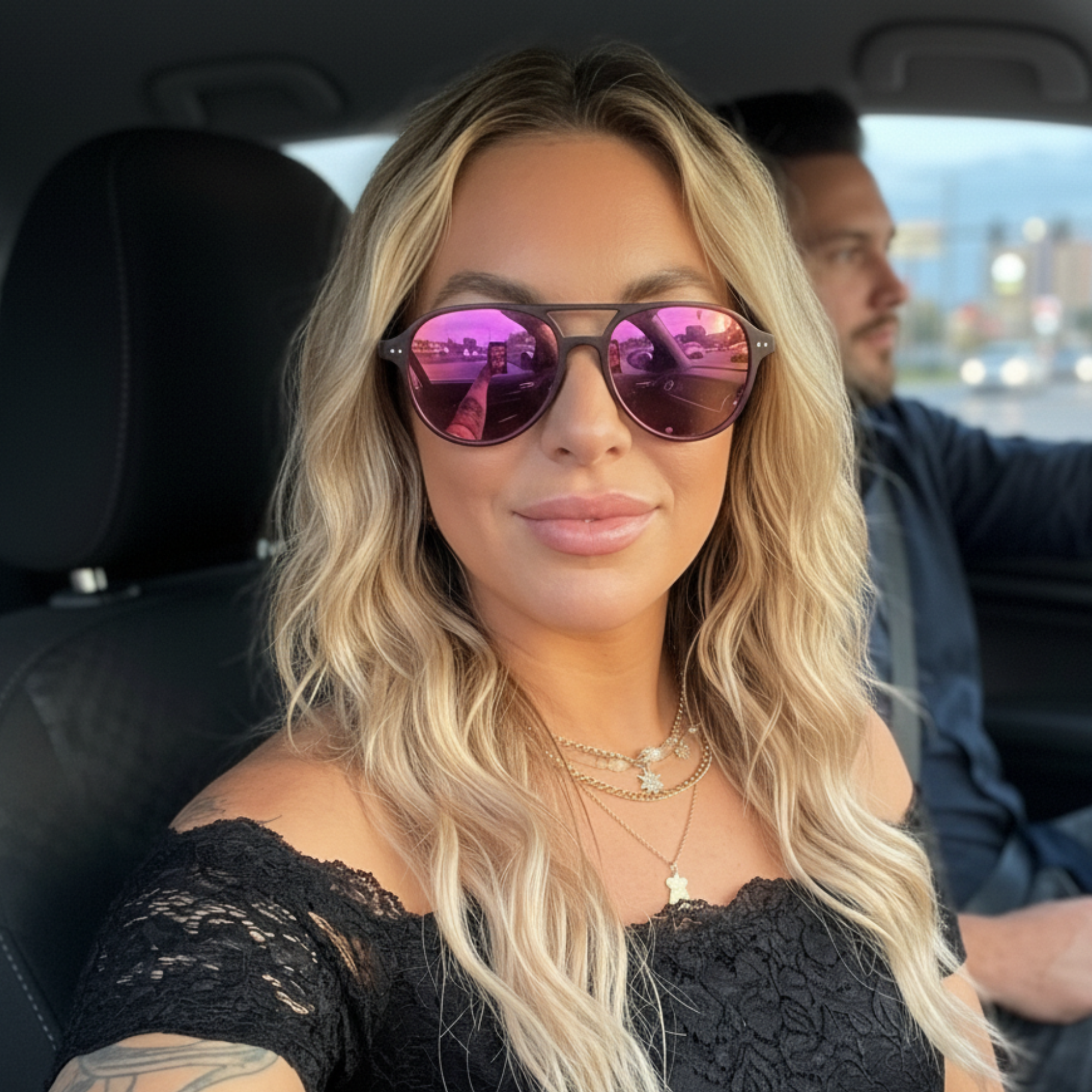 Woman wearing pink sunglasses sitting in a car with a blurred background