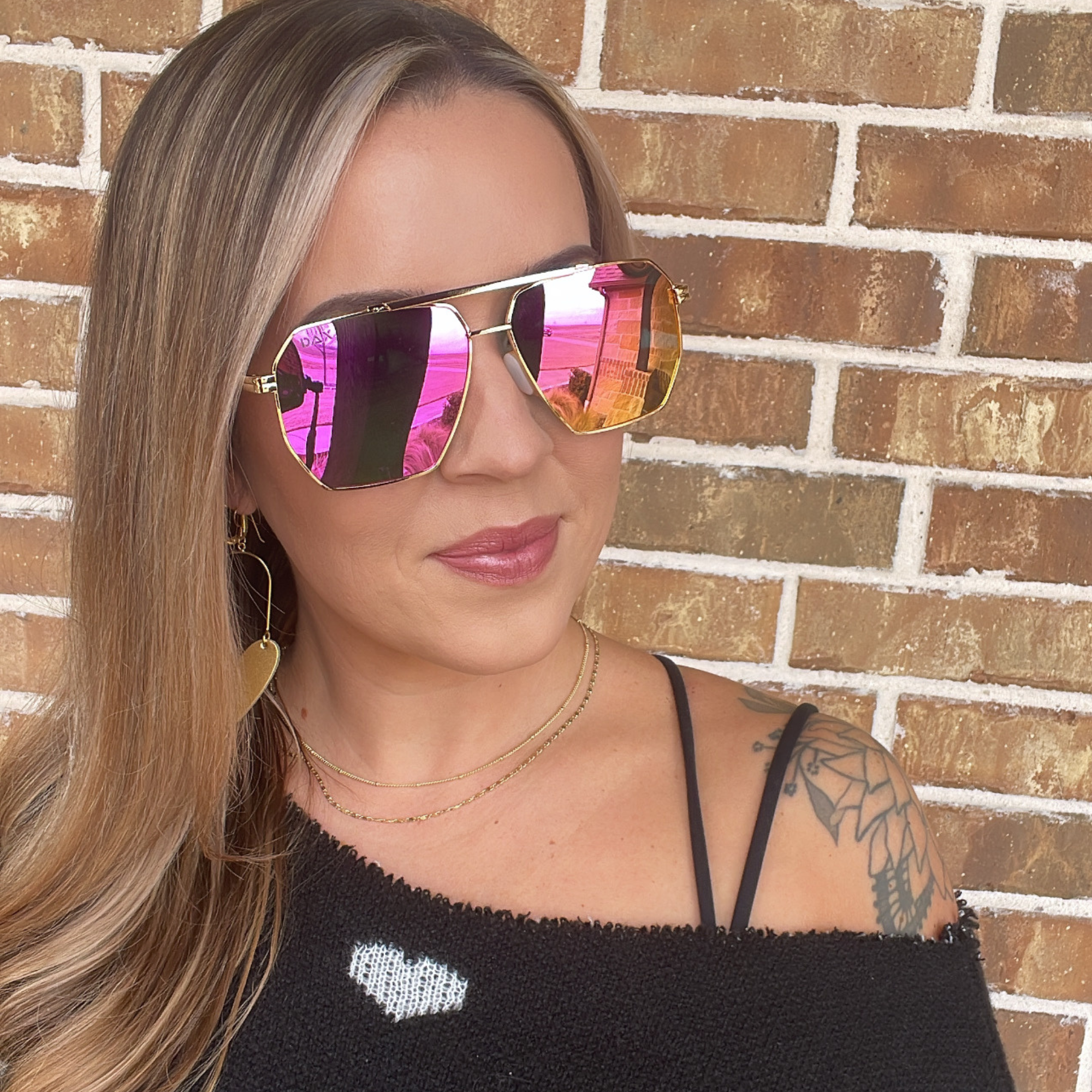 Woman wearing reflective sunglasses with a brick wall background