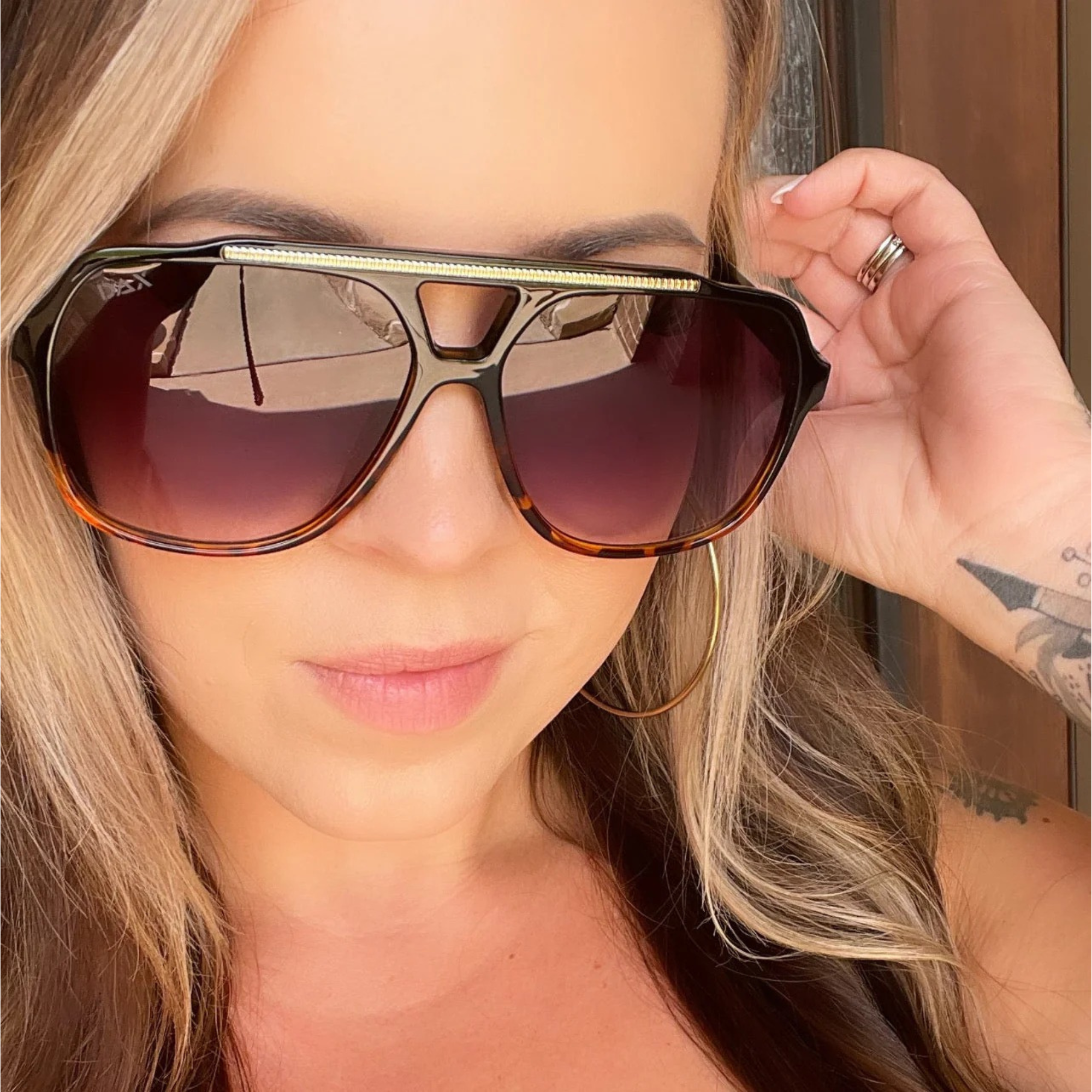 Close-up of a person wearing large sunglasses with a blurred background