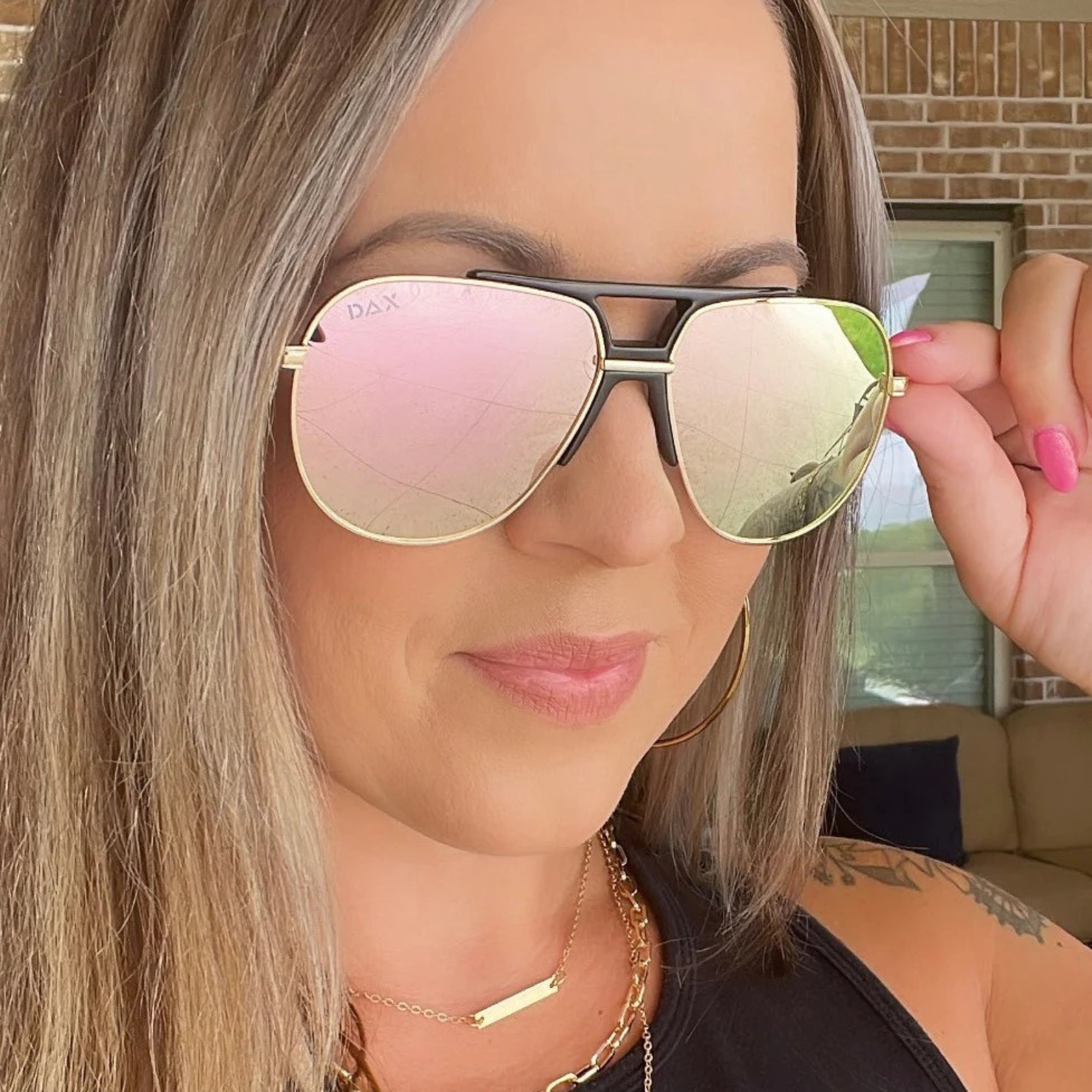 Woman wearing a pair of sunglasses with pink lenses, indoors.