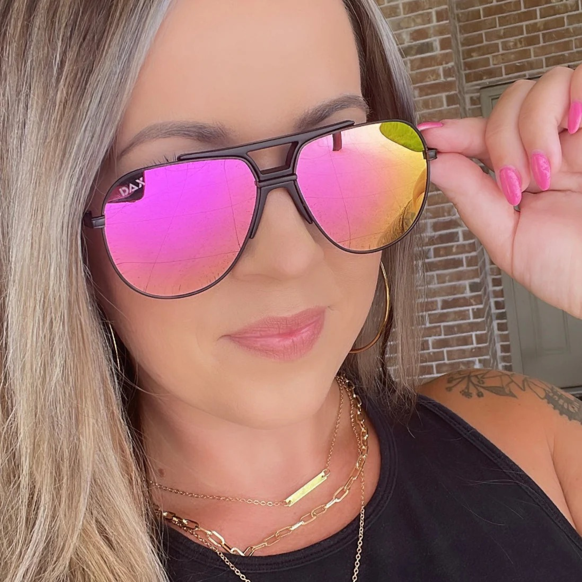 Woman wearing pink reflective sunglasses with a blurred background