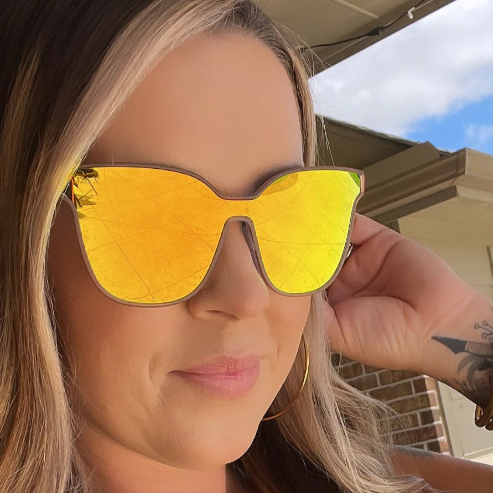 Woman wearing yellow sunglasses with a blurred background