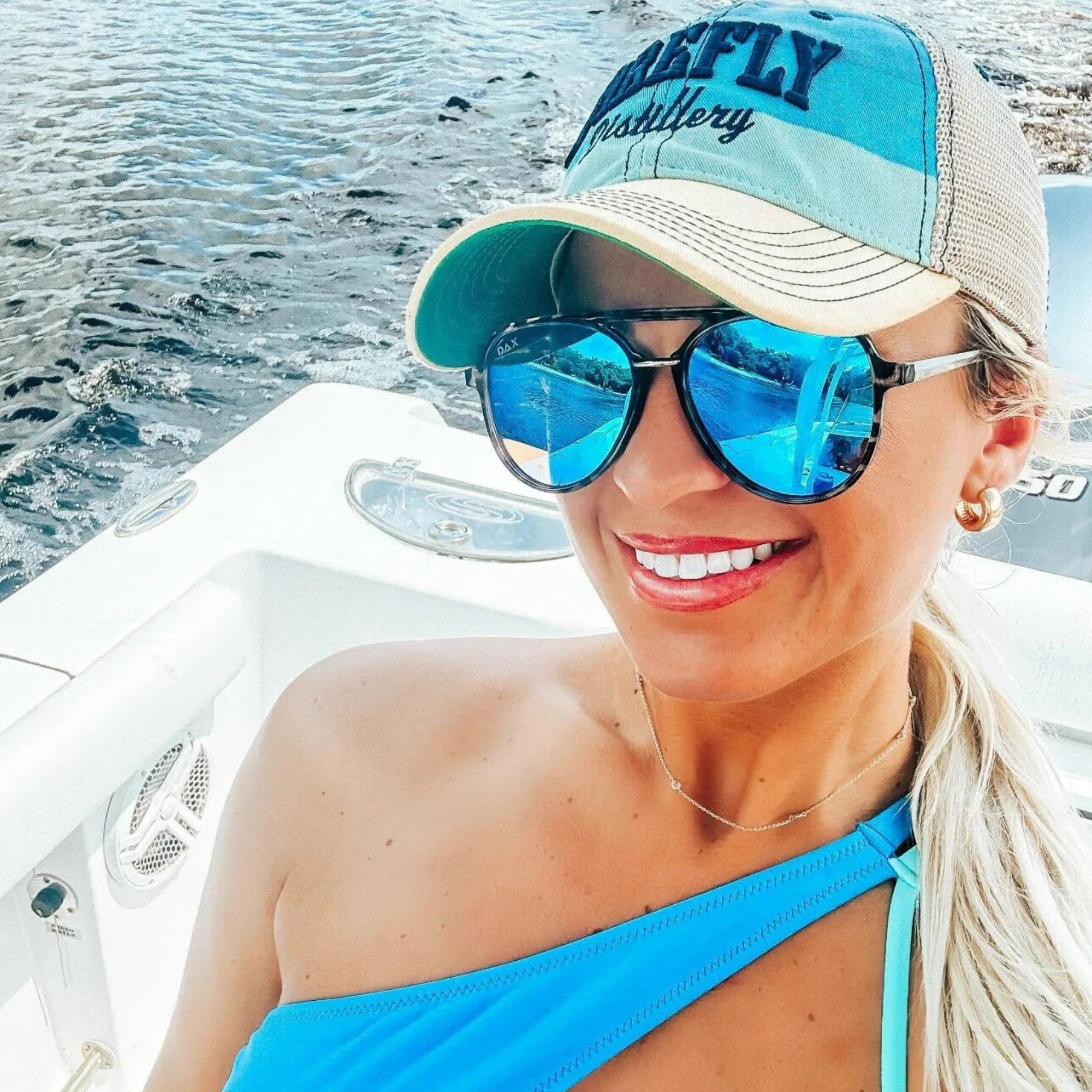 Woman wearing a blue cap and sunglasses on a boat with water in the background
