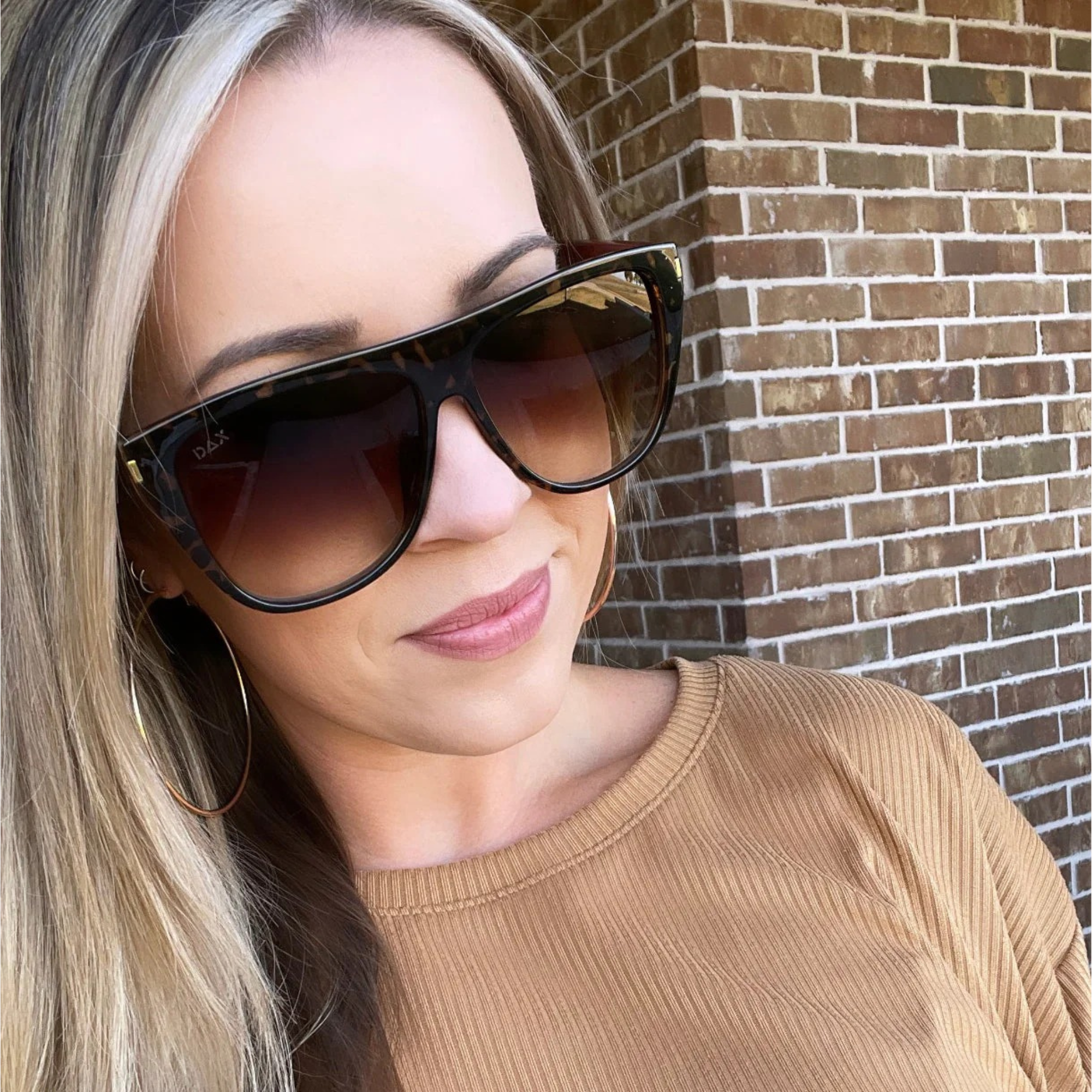 Woman wearing sunglasses with a brick wall background