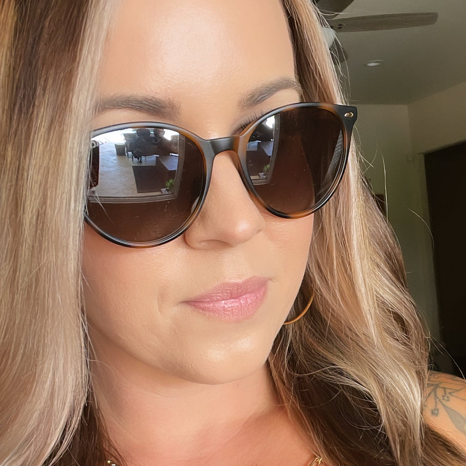 Close-up of a person wearing sunglasses with a neutral background