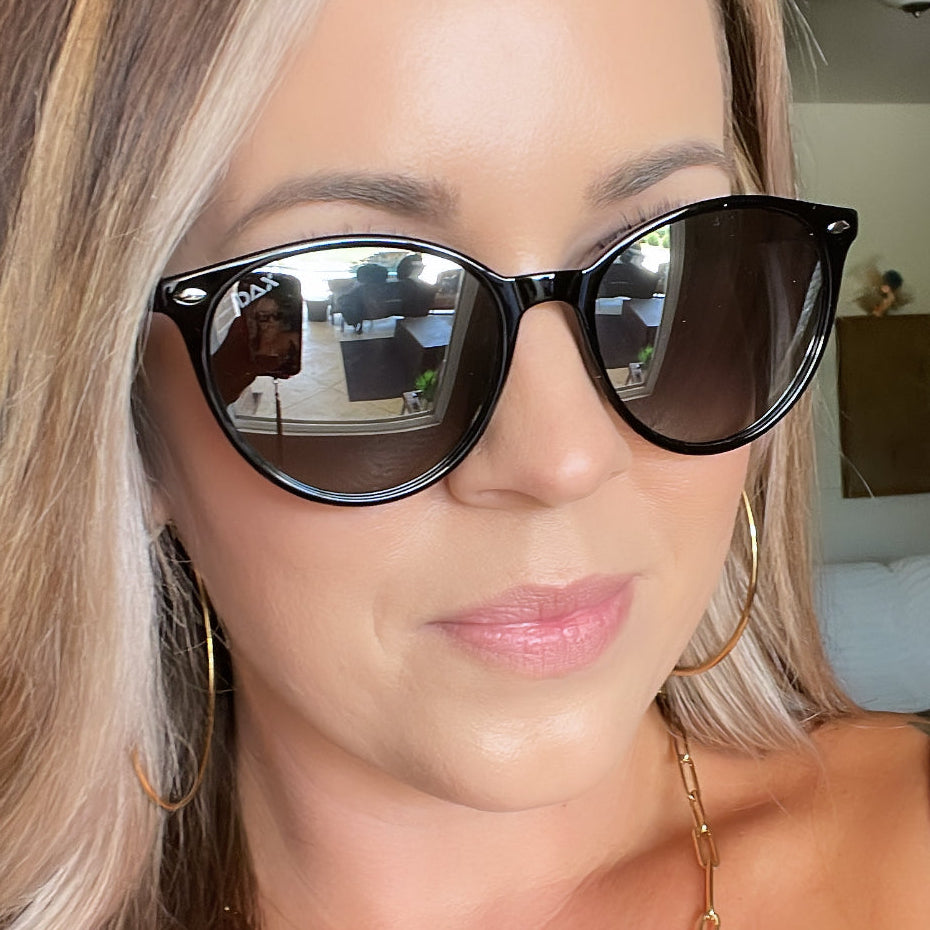Close-up of a person wearing black sunglasses with a blurred indoor background