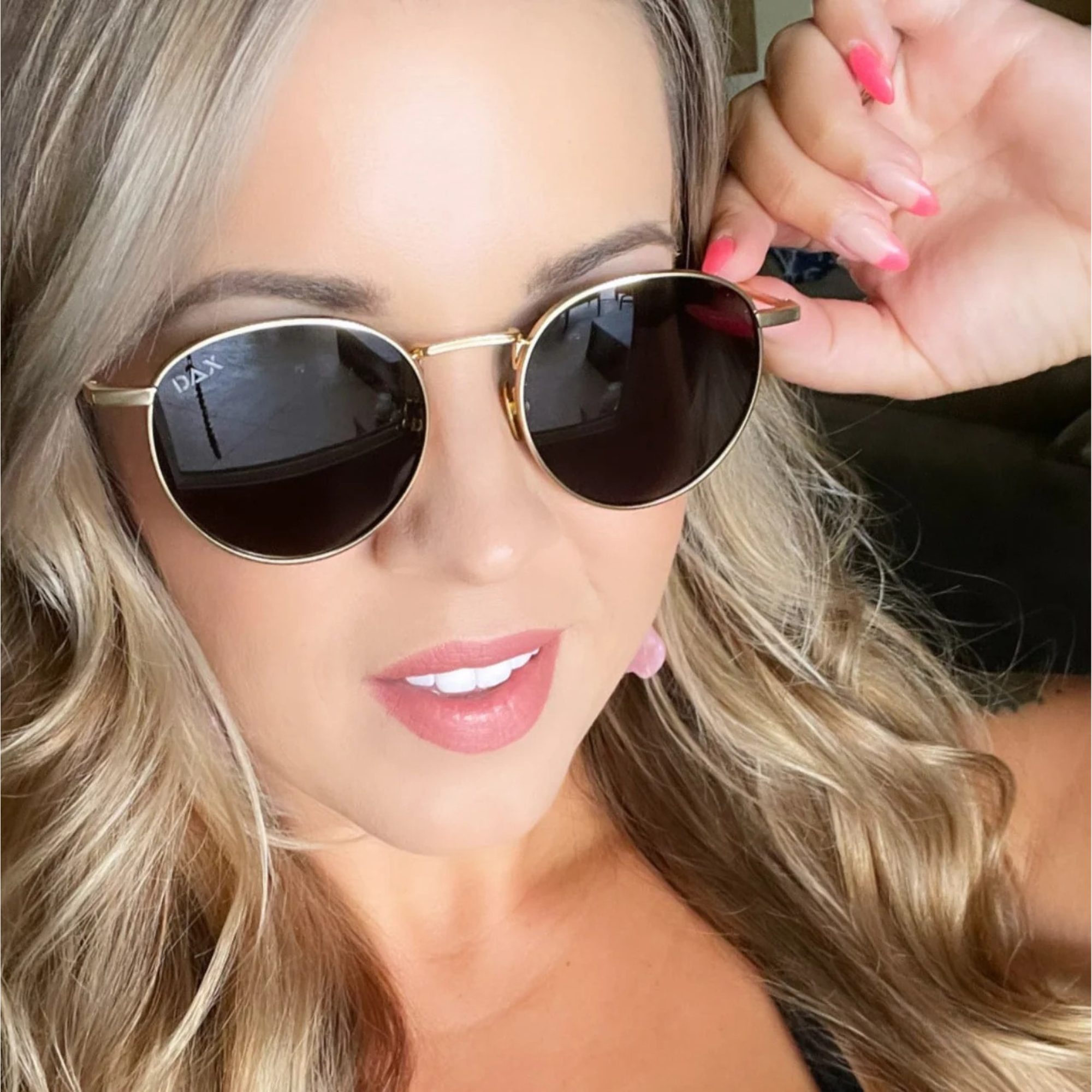 Woman wearing round sunglasses with a blurred background