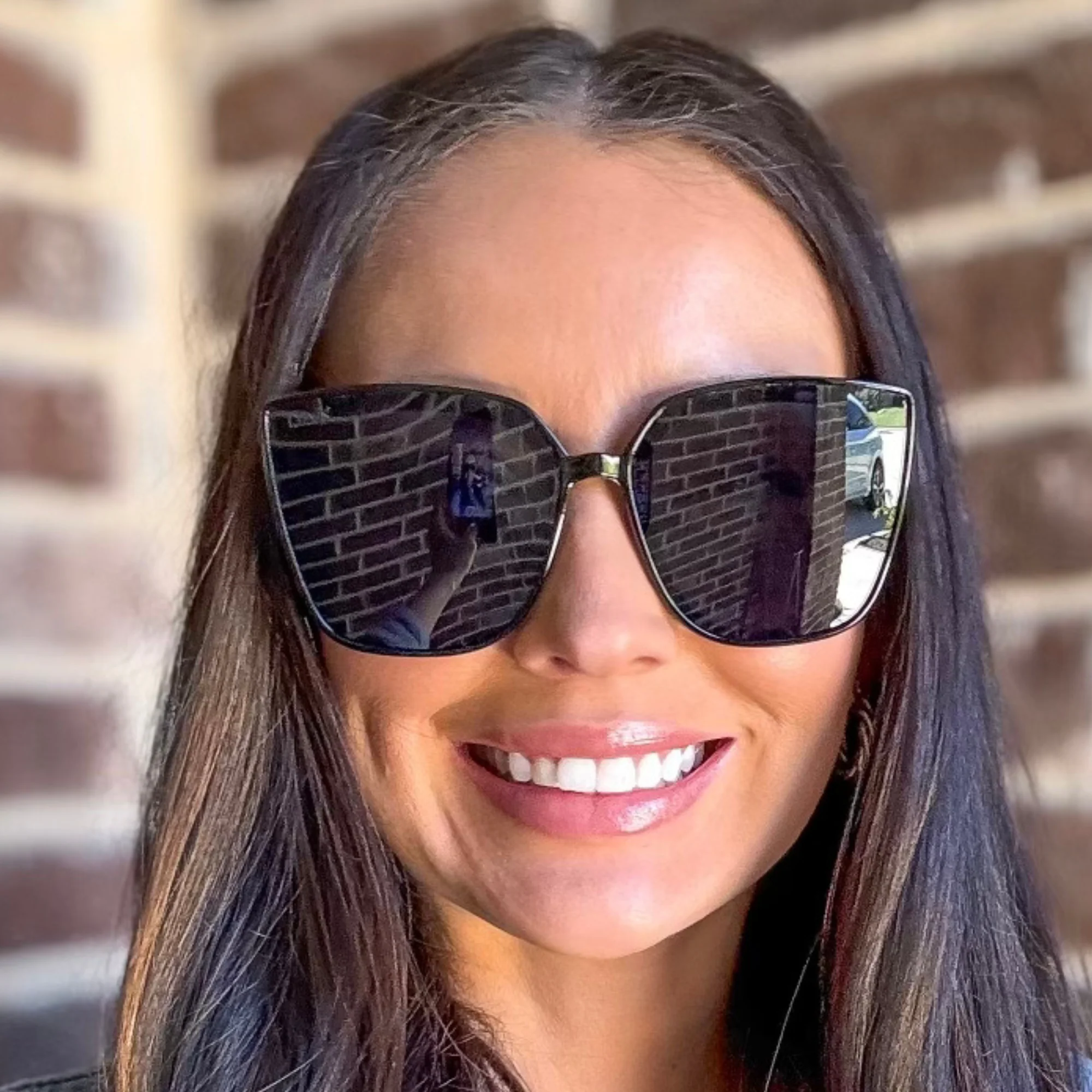 Woman wearing sunglasses with a brick wall background