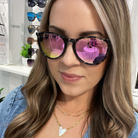 Woman wearing pink-tinted sunglasses with a store interior in the background