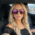 Woman wearing pink sunglasses sitting in a car with a blurred background