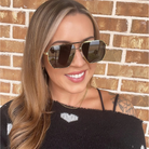 Woman wearing sunglasses in front of a brick wall