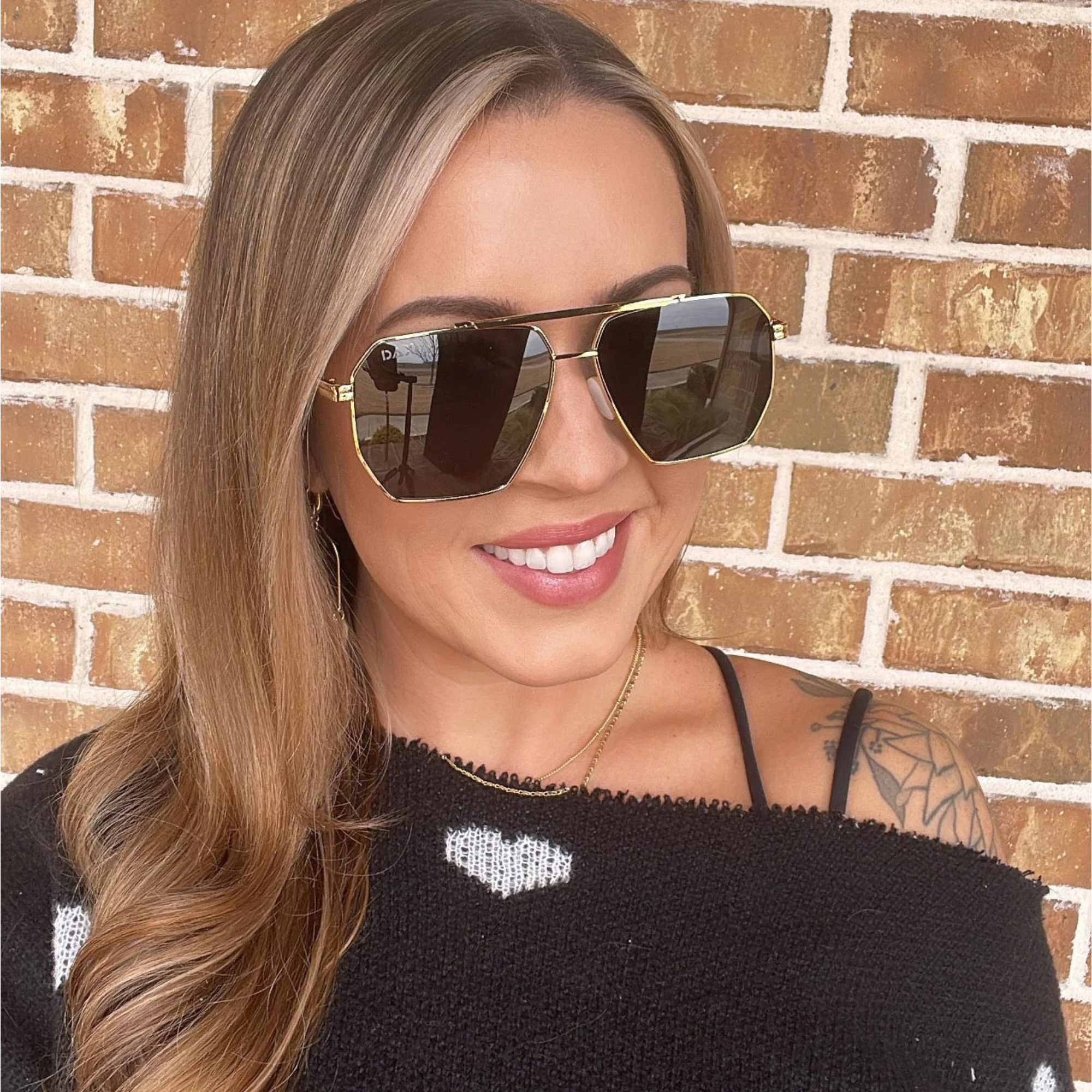 Woman wearing sunglasses in front of a brick wall