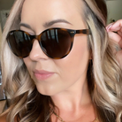 Close-up of a person wearing tortoiseshell sunglasses with a blurred background