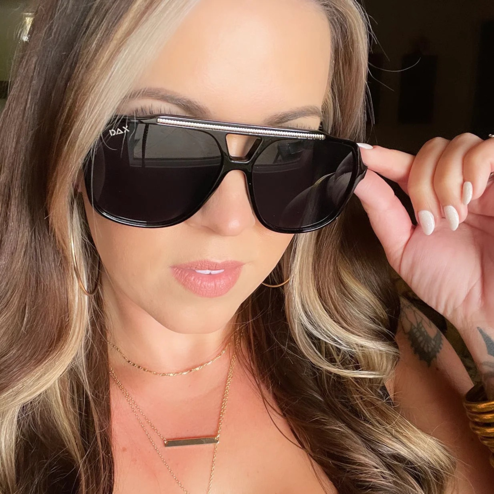 Woman holding a pair of sunglasses with a blurred background