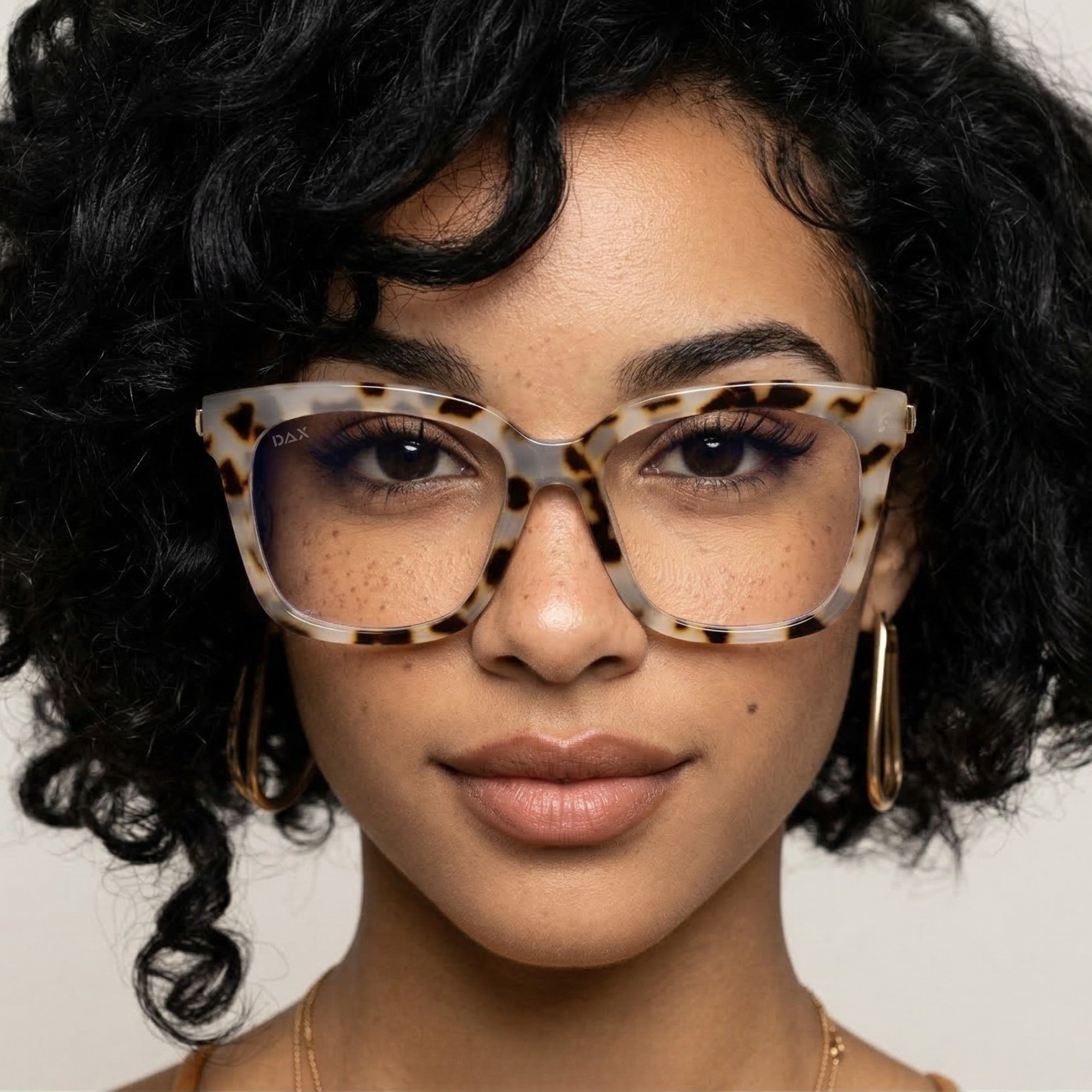 Woman wearing tortoiseshell glasses with a neutral background