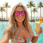 Woman holding a tropical drink by a pool with palm trees in the background