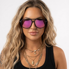 Woman wearing pink-tinted sunglasses with a plain background