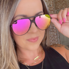 Woman wearing pink reflective sunglasses with a blurred background