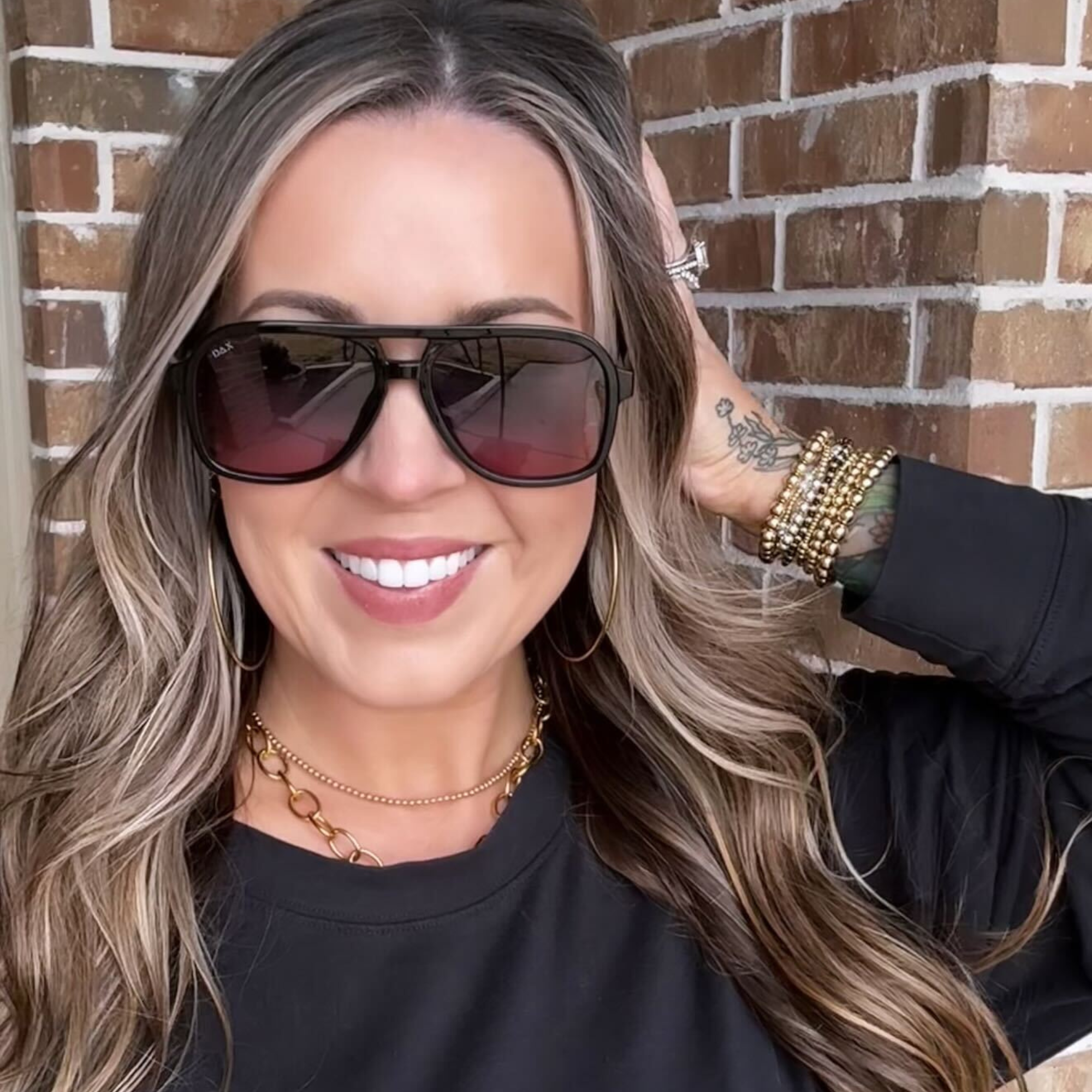 Woman wearing sunglasses with a brick wall background