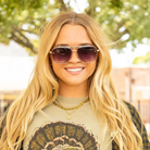 Woman wearing sunglasses and a graphic t-shirt with a blurred outdoor background