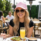 Woman sitting outdoors at a table with a glass of orange juice, a cup of coffee, and a plate of food.