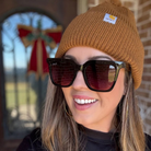 Person wearing a brown knit beanie and sunglasses with a blurred background