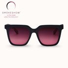 Black sunglasses with pink gradient lenses on a white background, featuring the Smokeshow logo.