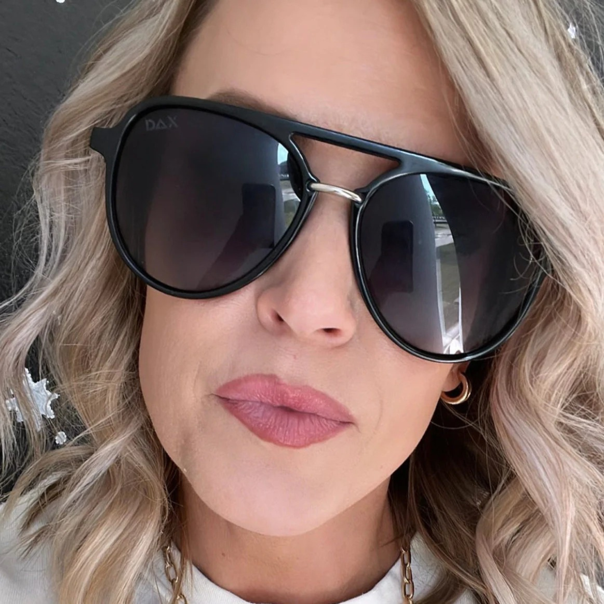 Close-up of a person wearing black sunglasses with a neutral background