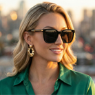Woman wearing sunglasses and a green shirt with a blurred cityscape background