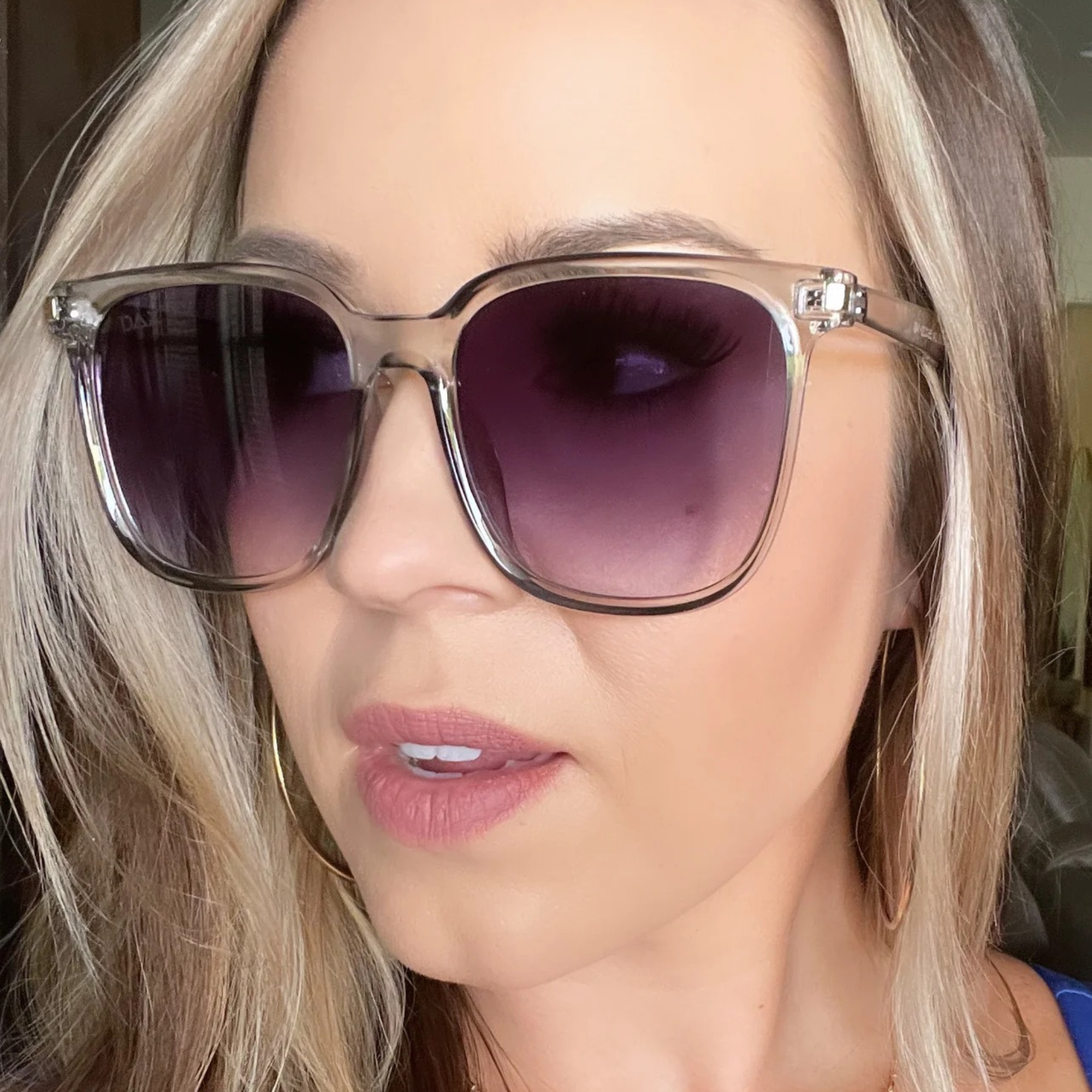 Close-up of a person wearing sunglasses with purple lenses.