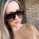 Woman wearing sunglasses with a brick wall background