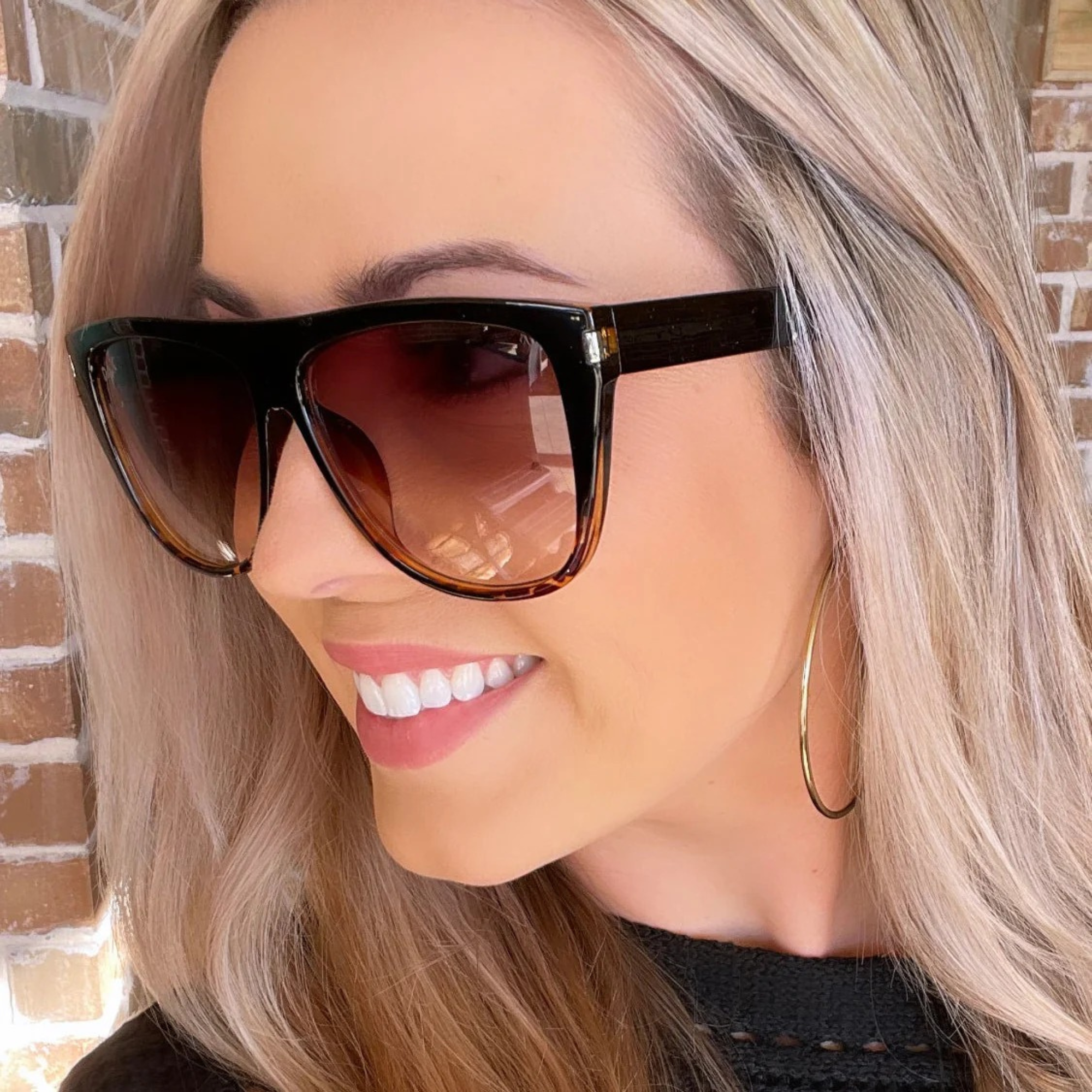 Woman wearing sunglasses with a brick wall background