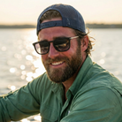 Man wearing sunglasses and a cap by a body of water