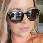 Close-up of a person wearing black sunglasses with a blurred indoor background