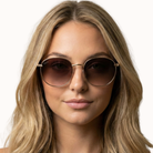 Woman wearing round sunglasses with a plain background