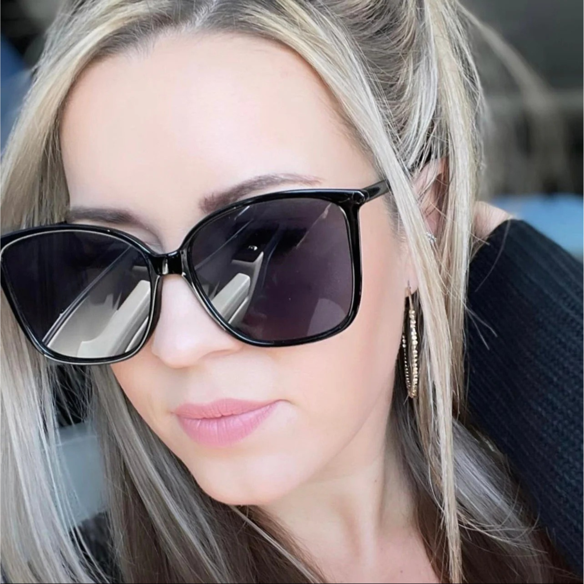 Close-up of a woman wearing black sunglasses with a blurred background