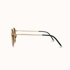 Sunglasses with gold frame and black arms on a white background