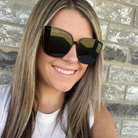 Woman wearing black sunglasses with a brick wall background