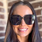Woman wearing sunglasses with a brick wall background