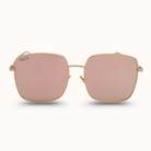 Gold-framed sunglasses with pink lenses on a white background