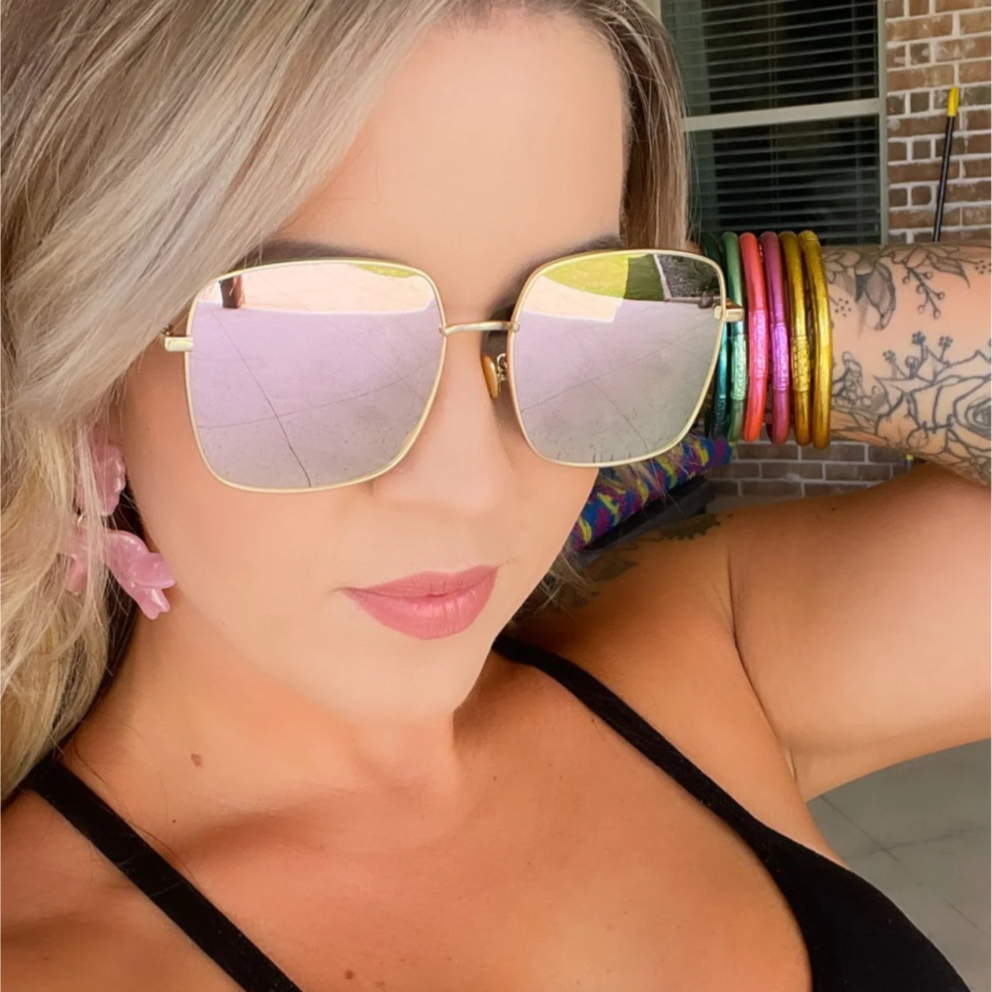 Woman wearing large reflective sunglasses with a colorful background