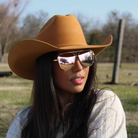 Woman wearing a brown cowboy hat and sunglasses outdoors