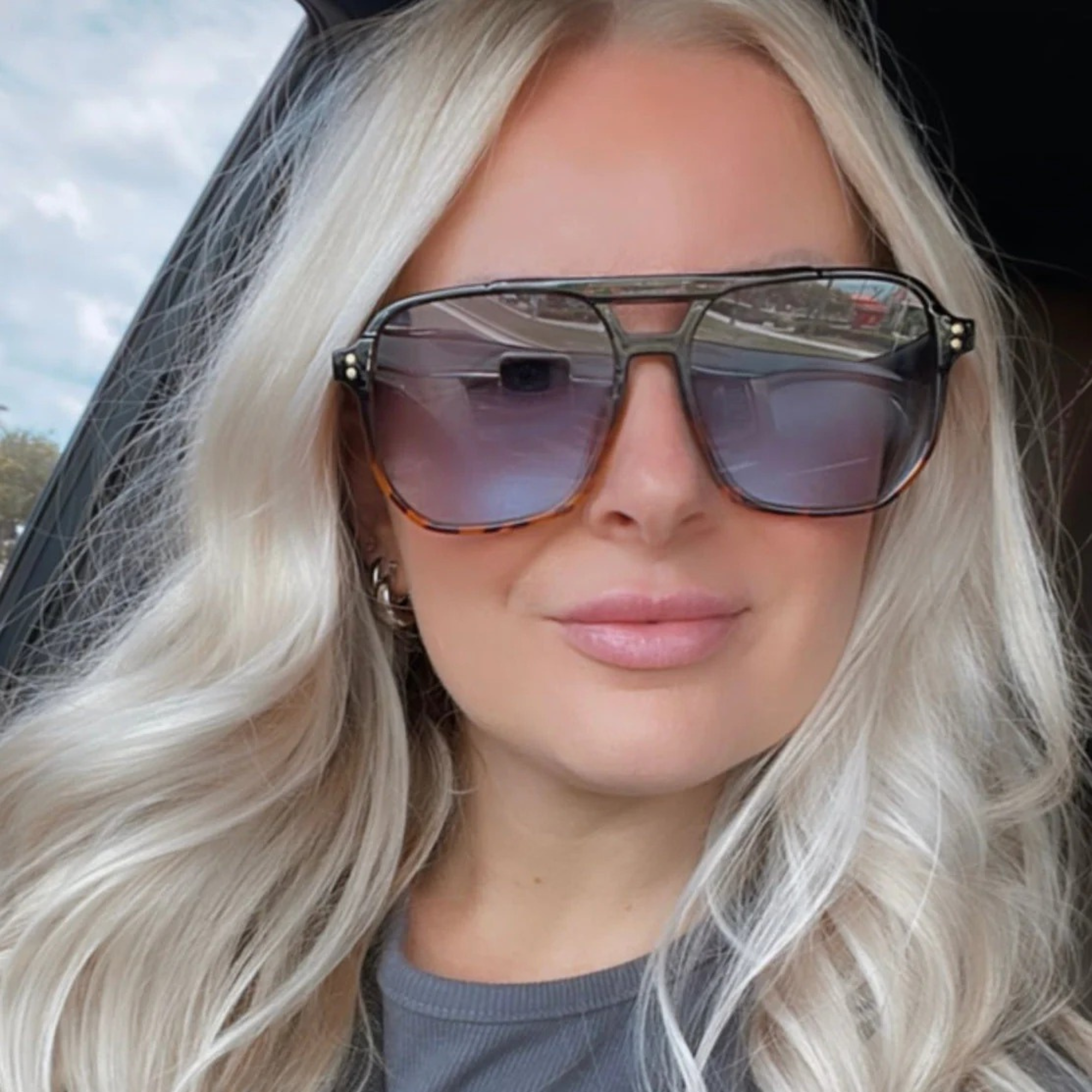 Woman wearing large sunglasses with a blurred outdoor background