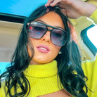 Woman wearing sunglasses and a yellow top inside a vehicle