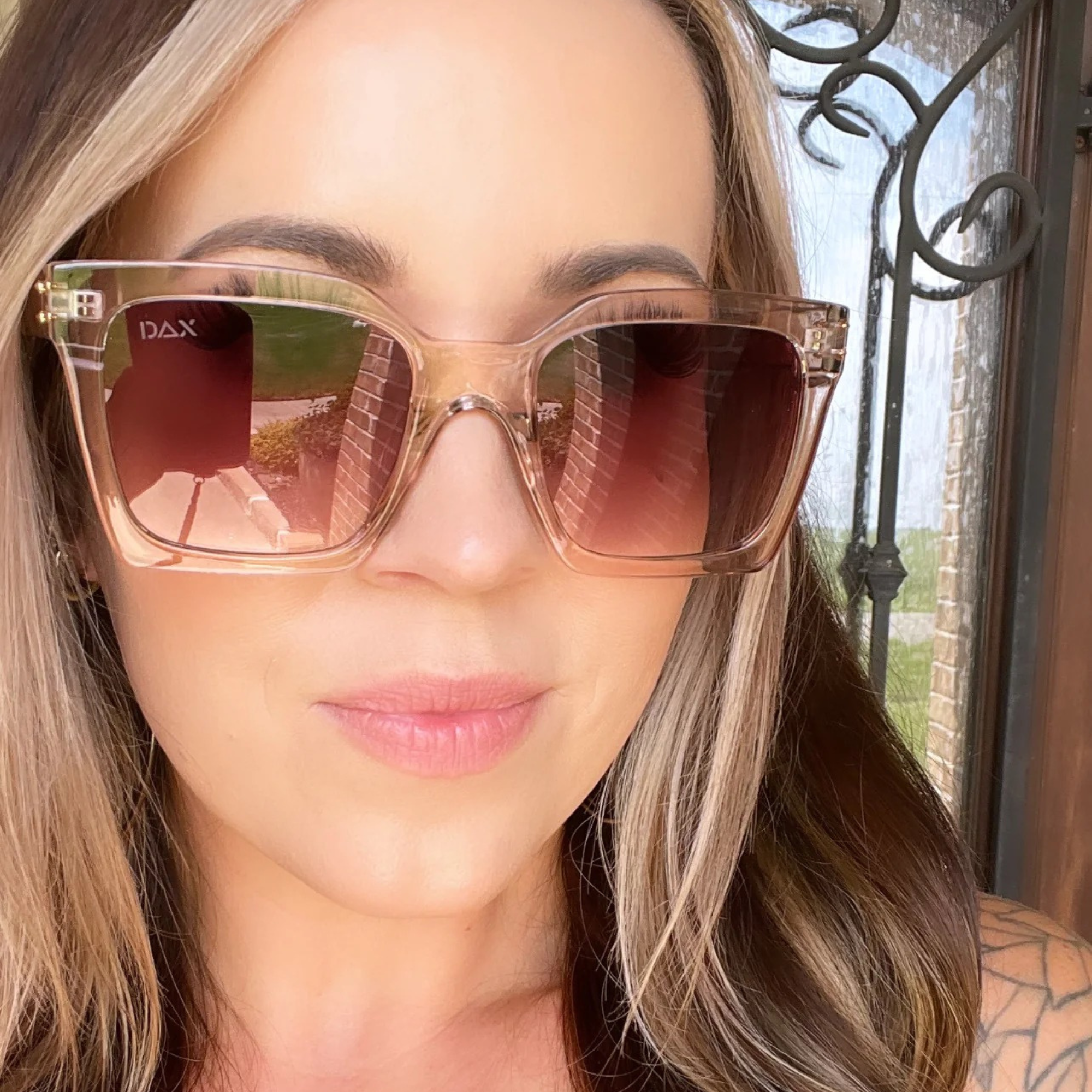 Woman wearing DAX sunglasses with a blurred outdoor background